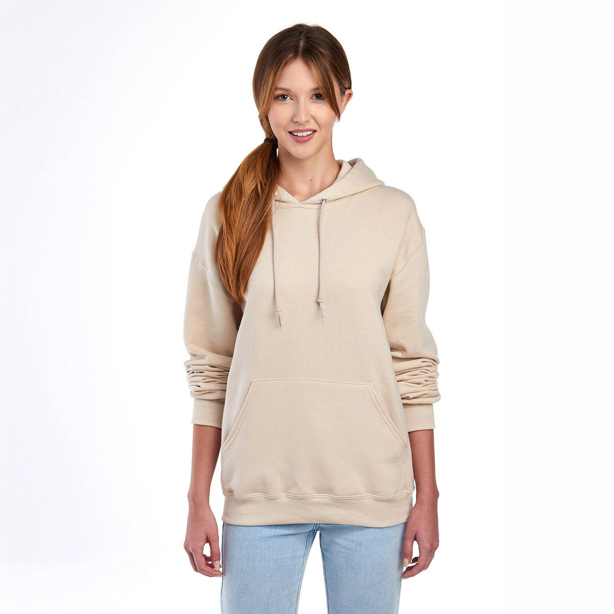 A woman wearing a Jerzees NuBlend Unisex Hooded Sweatshirt in sandstone.