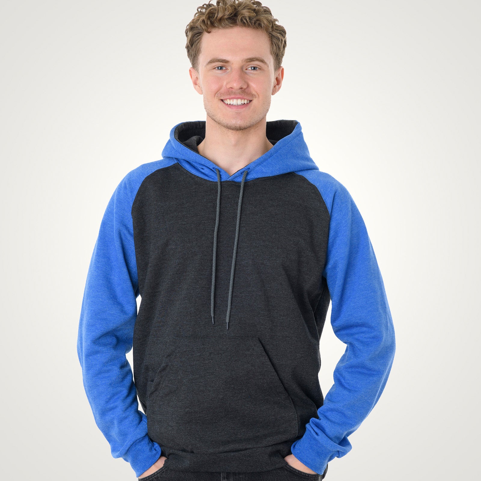 Young man wearing a King Athletics Raglan Hooded Sweatshirt in dark charcoal heather with blue sleeves.
