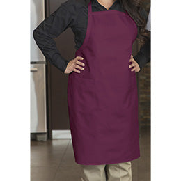 A person wearing a burgundy Premium Uniforms designer bib apron with front pockets.