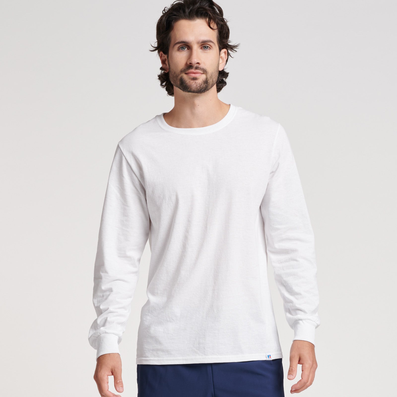 Model wearing a white Russell Athletic DRI-POWER CVC Performance unisex long-sleeve t-shirt.