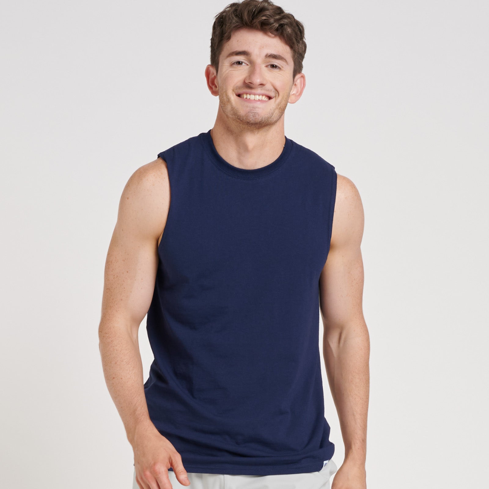 A man wearing a navy Russell Athletic DRI-POWER CVC Performance unisex muscle T-shirt, smiling against a white background.