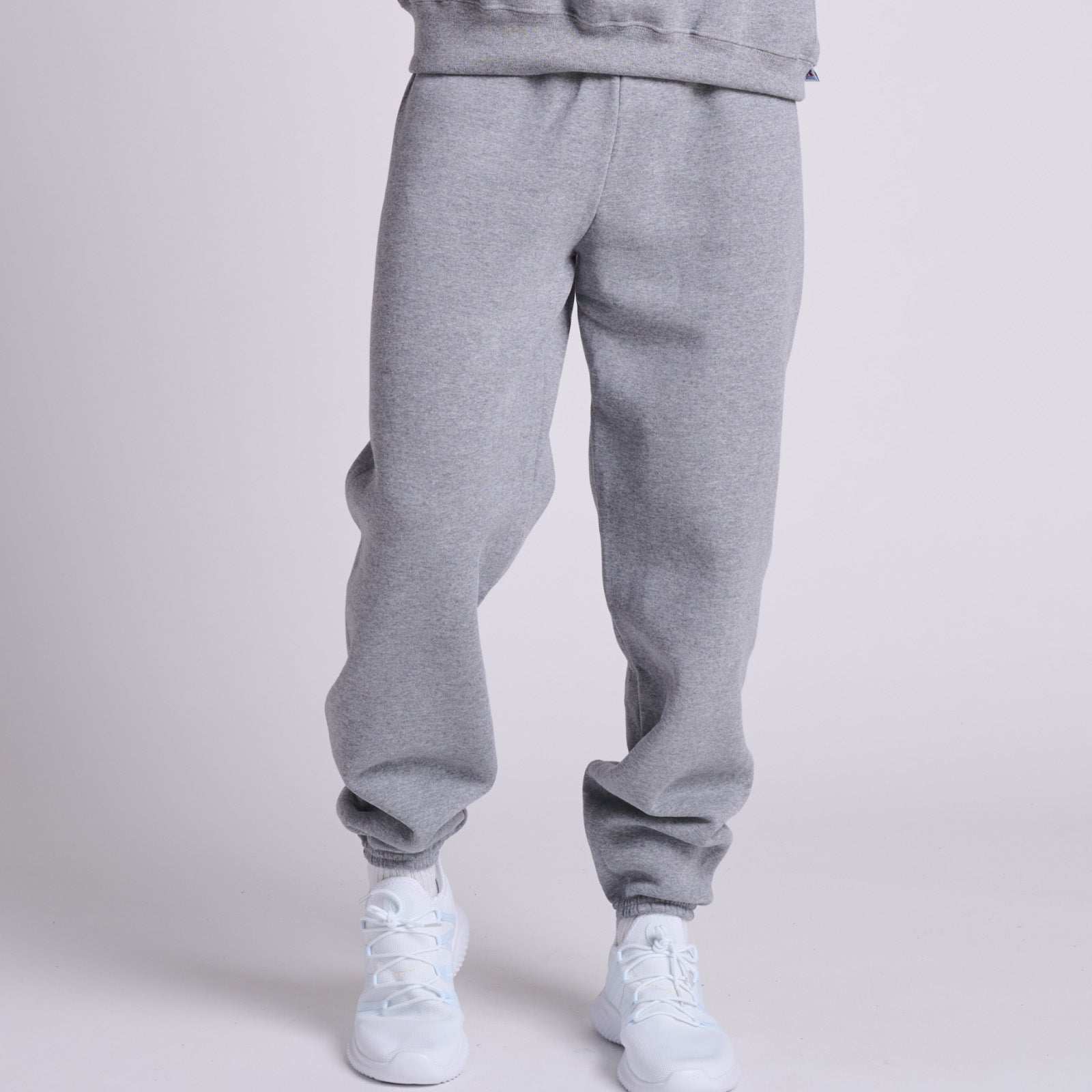 Russell Athletic DRI-POWER adult closed-bottom sweatpants in oxford grey worn with white athletic sneakers.