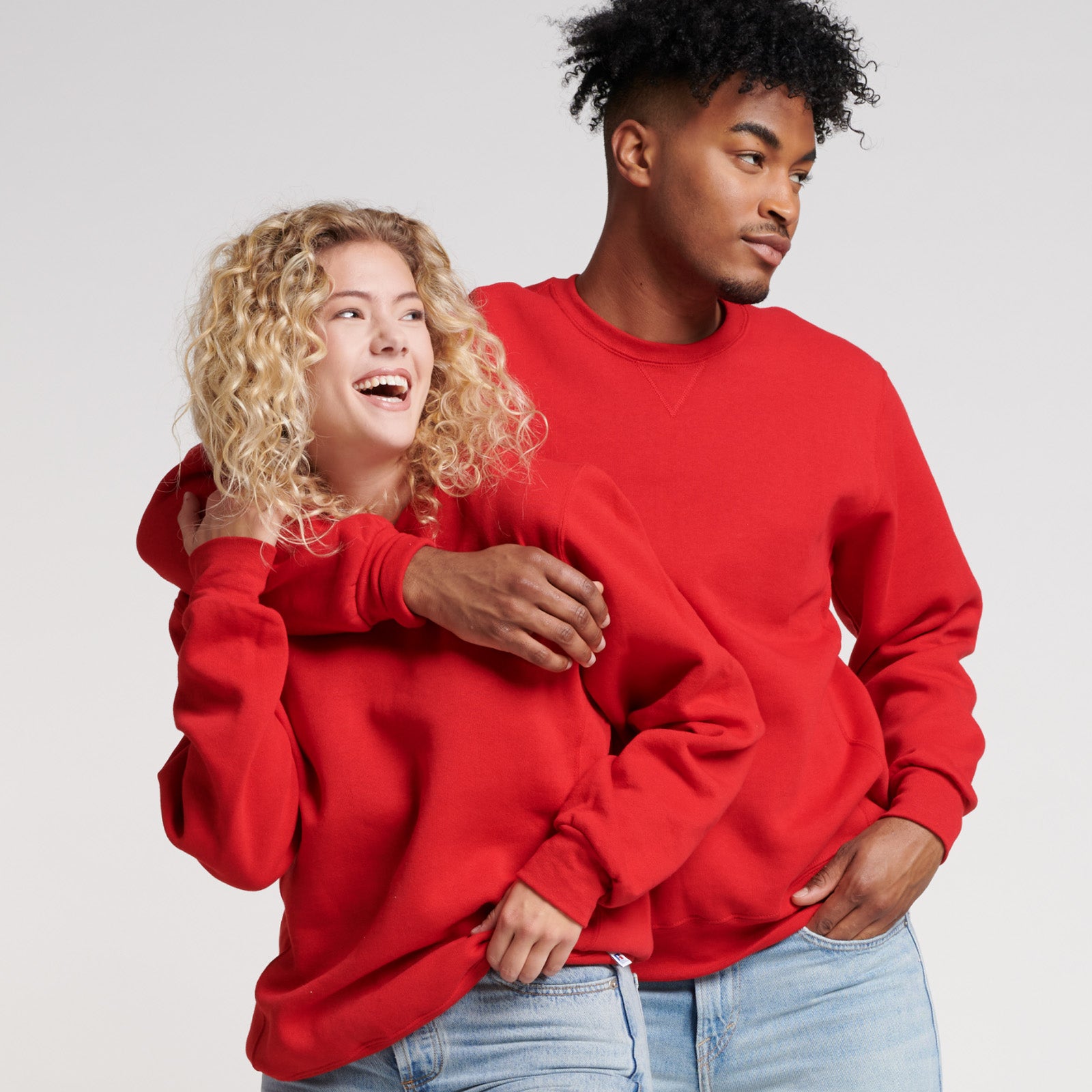 Man and woman wearing Russell Athletic DRI-POWER Adult Fleece Crew in True Red against a plain background.
