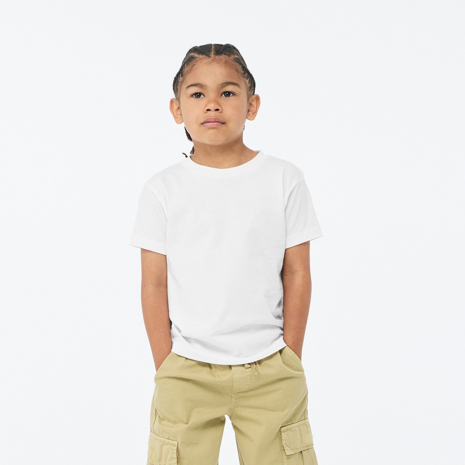A young boy wearing a white Bella+Canvas Youth Jersey Short Sleeve Tee with khaki cargo pants against a white background.
